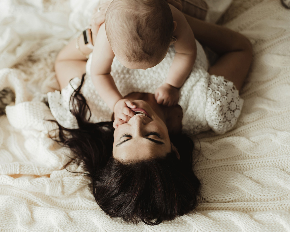 yatakta uzanmış anne ve bebeğin beraber etkileşimi